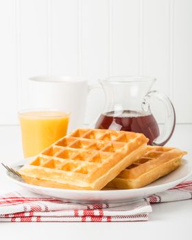 Stack of fresh made waffles with coffee and juice.