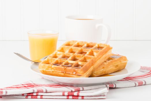 Fresh made waffles and maple syrup served with juice and coffee.