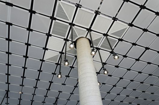 Bare concrete column with suspended ceiling in modern building