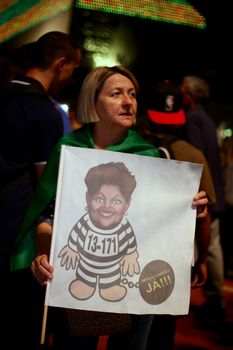 BRAZIL, Sao Paulo: A woman holds a drawing of Brazilian President Dilma Rousseff dressed-up as a prisoner, as thousands gather on the Paulista Avenue, in Sao Paulo, during a pro-impeachment rally, on March 16, 2016. Outraged Brazilians protested in Brasilia and Sao Paulo following the release of a taped phone call between President Dilma Rousseff and her predecessor Luiz Inacio Lula da Silva. On Sunday, an estimated three million Brazilians flooded the streets in nationwide protests calling for Rousseff's departure.