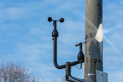 Weather station with anemometer on blue sky.