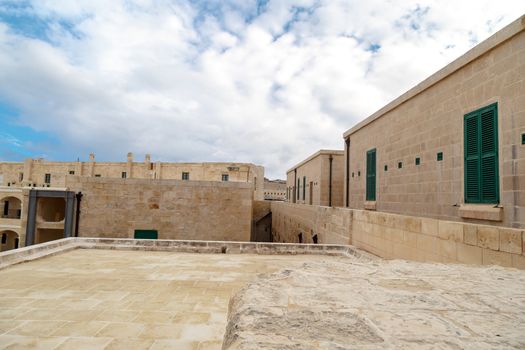 View of National War Museum in Valletta, Malta with high yellow stone walls, on cloudy sky background.