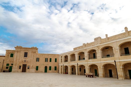 View of National War Museum in Valletta, Malta with high yellow stone walls, on cloudy sky background.