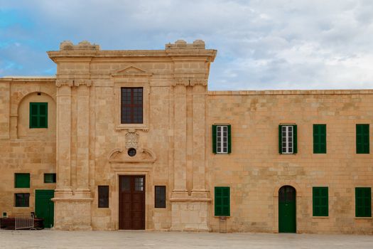 View of National War Museum in Valletta, Malta with high yellow stone walls, on cloudy sky background.