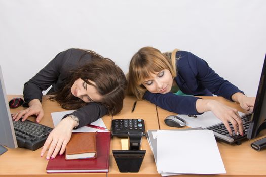 Two young office employee asleep on desk for computers