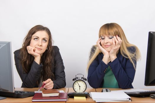 Two bored office worker waiting for the end of the day and look at the clock