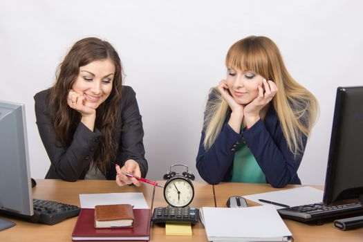 Two happy office workers checked against the clock at the end of the working day