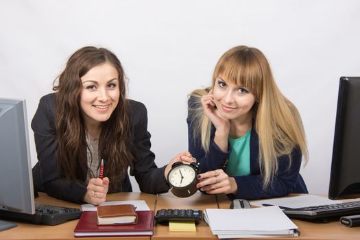 Two happy office workers checked against the clock at the end of the working day
