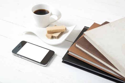 coffee cup with wafer,phone,stack of book on white wood background