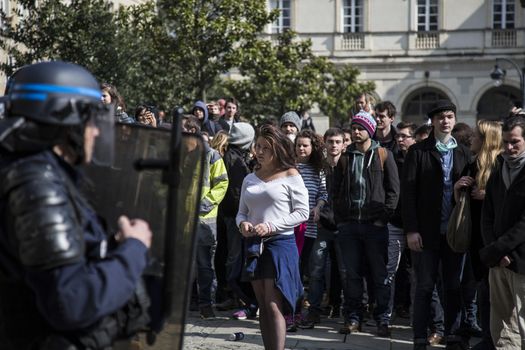 FRANCE, Paris: High school students and youths face policemen as they demonstrate in front of Rennes' town hall, western France,  during a protest march opposing the government's labour reforms on March 17, 2016. The contested reform is designed to inject more flexibility into the labour market by dropping key measures that would have benefited smaller companies. In a significant change from the original text, French Prime minister said on Monday that small and medium-sized companies would not be able to unilaterally introduce flexible work practices into their working week.