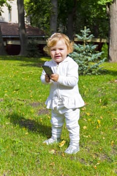 Caucasian beautiful cute infant girl in summer with mobile phone