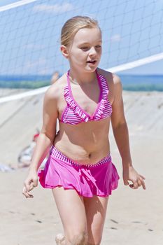 Photo of cute girl in pink swimsuit running on a beach