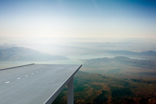 Road over mountains in blue sky and sun