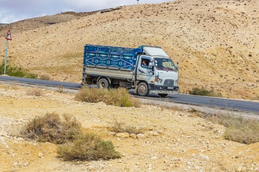 The truck down the road in a mountainous desert of Jordan. Jordan colorful truck.