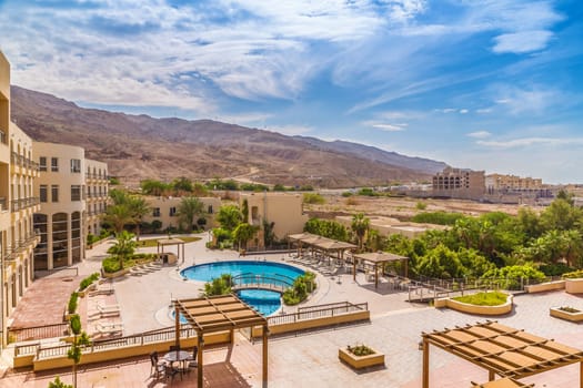 Hotel swimming pool with views of the desert mountains. Around the pool are growing tropical plants.