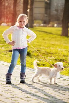 Little girl walking with her puppy dog in the park