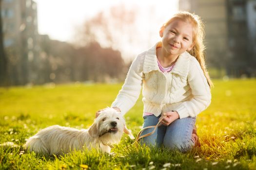 Little girl playing with her puppy dog in the park