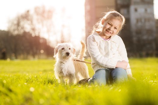 Little girl relaxing with her puppy dog in the park