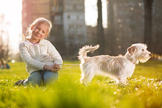 Little girl relaxing with her puppy dog in the park