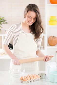 Happy young woman in the kitchen with Rolling Pin