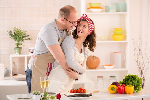 Happy boyfriend hugging her girlfriend in the kitchen.