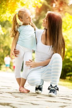 Beautiful mother and daughter having fun in the park on spring day.