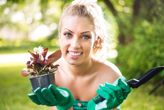 Portrait of Smiling young woman planting flowers in the garden.