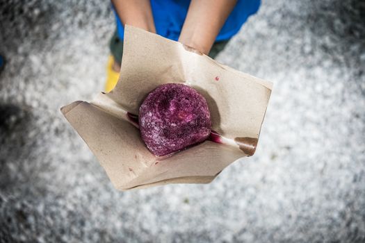 A top view shot of a person holding an ice ball with grape flavor.