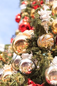 Red, green, gold, silver Christmas ornaments hanging on a Christmas tree in December