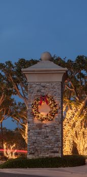 Christmas holiday wreath with white lights on a brick pillar