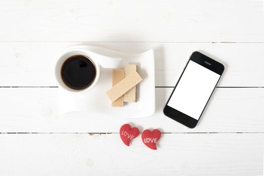 coffee cup with wafer,phone,heart on white wood background