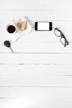 coffee cup with wafer,phone,car key,eyeglasses on white wood background