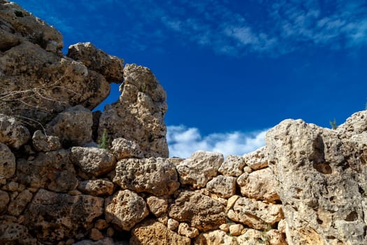 View of stone structures of ancient Ggantija Temples in Gozo Malta, on cloudy blue sky background.
