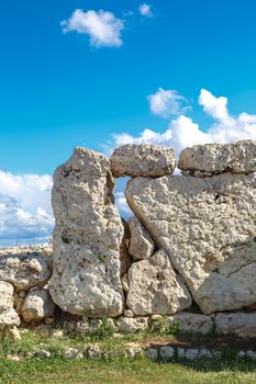 View of stone structures of ancient Ggantija Temples in Gozo Malta, on cloudy blue sky background.