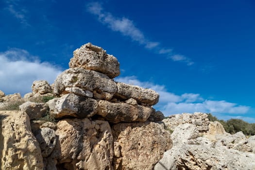 View of stone structures of ancient Ggantija Temples in Gozo Malta, on cloudy blue sky background.