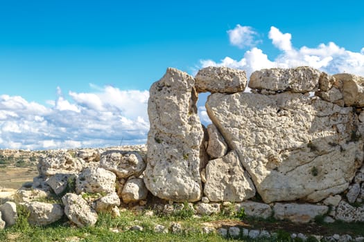 View of stone structures of ancient Ggantija Temples in Gozo Malta, on cloudy blue sky background.
