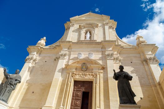 Bottom view of historical Cathedral of the Assumption in Gozo Malta, on cloudy blue sky background.