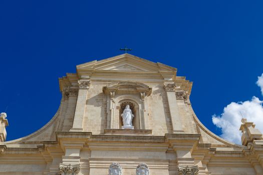 Bottom view of historical Cathedral of the Assumption in Gozo Malta, on cloudy blue sky background.