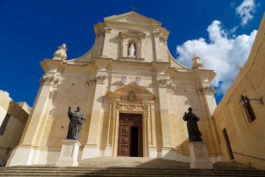 Bottom view of historical Cathedral of the Assumption in Gozo Malta, on cloudy blue sky background.