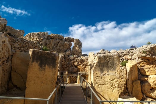 View of stone structures of ancient Ggantija Temples in Gozo Malta, on cloudy blue sky background.
