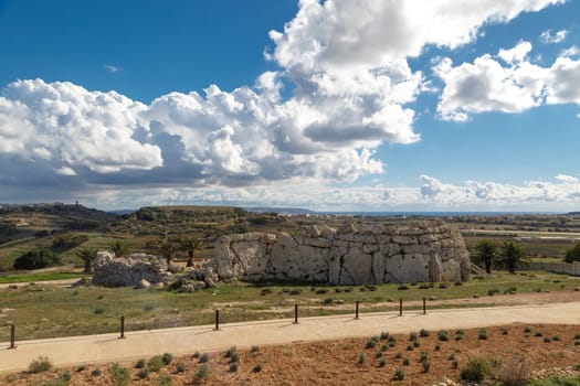 View of stone structures of ancient Ggantija Temples in Gozo Malta, on cloudy blue sky background.