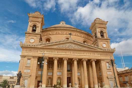 MOSTA, MALTA - NOVEMBER 1, 2015 : Exterior view of Rotunda of Malta known as also Mosta Dome, historical and the third biggest church in Europe, on cloudy blue sky background.
