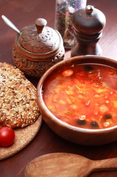 Nice wooden bowl with soup near bread and seasoning