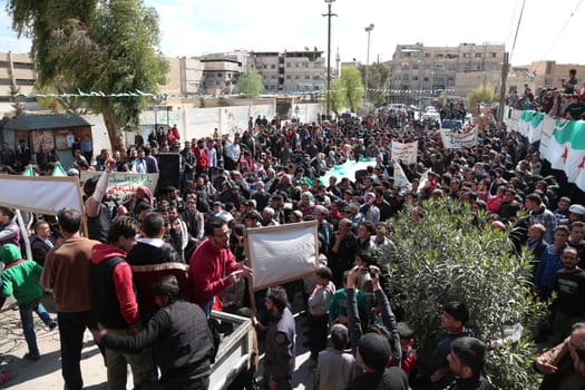SYRIA, Saqba: Protesters hold pre-Baath Syrian flags, adopted during the uprising in 2011, and placards during an anti-regime demonstration in the rebel-held town of Saqba, on the outskirts of the Syrian capital Damascus, on March 18, 2016. Syria's war is entering its sixth year with a glimmer of hope that a landmark ceasefire and a push for peace could help resolve a conflict that has sent hundreds of thousands fleeing to Europe. The conflict began with anti-regime protests in mid-March 2011 and spiralled into a bloody war after a harsh government crackdown on demonstrators.
