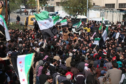 SYRIA, Saqba: Protesters hold pre-Baath Syrian flags, adopted during the uprising in 2011, and placards during an anti-regime demonstration in the rebel-held town of Saqba, on the outskirts of the Syrian capital Damascus, on March 18, 2016. Syria's war is entering its sixth year with a glimmer of hope that a landmark ceasefire and a push for peace could help resolve a conflict that has sent hundreds of thousands fleeing to Europe. The conflict began with anti-regime protests in mid-March 2011 and spiralled into a bloody war after a harsh government crackdown on demonstrators.