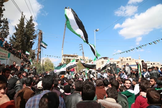 SYRIA, Saqba: Protesters hold pre-Baath Syrian flags, adopted during the uprising in 2011, and placards during an anti-regime demonstration in the rebel-held town of Saqba, on the outskirts of the Syrian capital Damascus, on March 18, 2016. Syria's war is entering its sixth year with a glimmer of hope that a landmark ceasefire and a push for peace could help resolve a conflict that has sent hundreds of thousands fleeing to Europe. The conflict began with anti-regime protests in mid-March 2011 and spiralled into a bloody war after a harsh government crackdown on demonstrators.