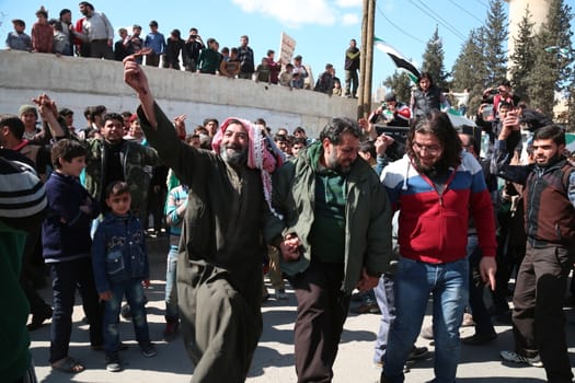 SYRIA, Saqba: Protesters hold pre-Baath Syrian flags, adopted during the uprising in 2011, and placards during an anti-regime demonstration in the rebel-held town of Saqba, on the outskirts of the Syrian capital Damascus, on March 18, 2016. Syria's war is entering its sixth year with a glimmer of hope that a landmark ceasefire and a push for peace could help resolve a conflict that has sent hundreds of thousands fleeing to Europe. The conflict began with anti-regime protests in mid-March 2011 and spiralled into a bloody war after a harsh government crackdown on demonstrators.