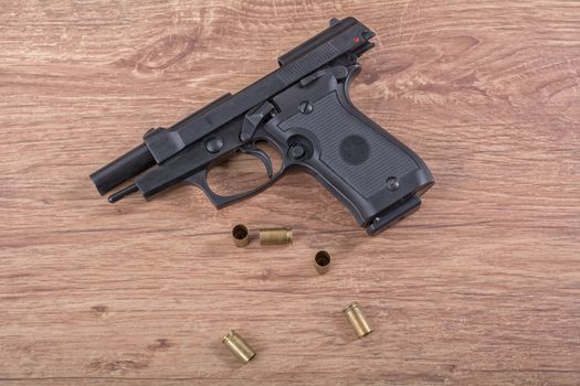 The gun with the bullets on a brown wooden background
