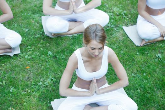 Women sitting in lotus position during yoga training at park