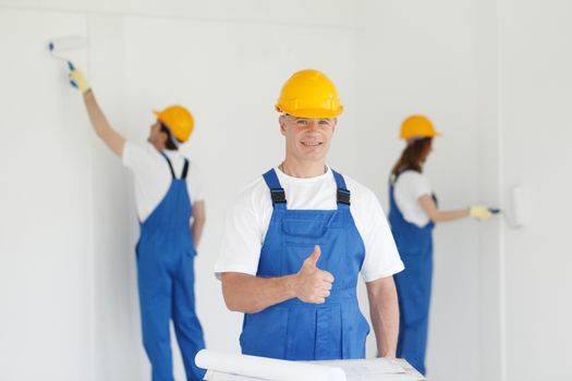 Workman gives thumbs up in front of two painters